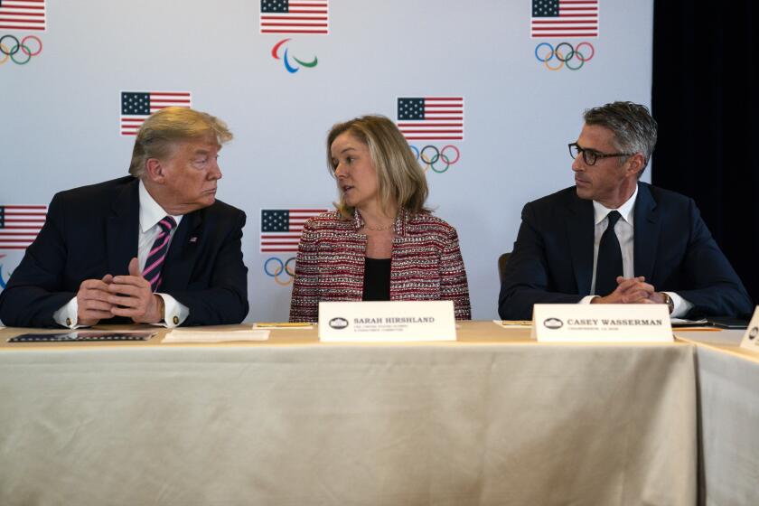 President Donald Trump, left, and LA 2028 Committee Chairman Casey Wasserman, right, listen as CEO of the United States Olympic and Paralympic Committee Sarah Hirshland speaks during a briefing with the U.S. Olympic and Paralympic Committee and Los Angeles 2028 organizers, Tuesday, Feb. 18, 2020, in Beverly Hills, Calif. (AP Photo/Evan Vucci)