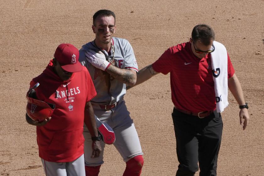 Los Angeles Angels' Zach Neto holds his shoulder as he heads to the dugout.