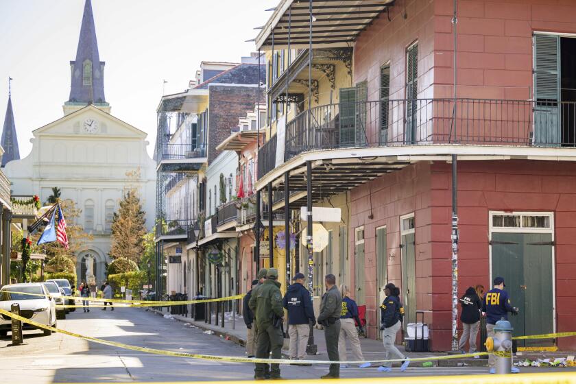 Members of the FBI work on Orleans Street and Bourbon Street by St. Louis Cathedral in the French Quarter near where a suspicious package was detonated during the investigation of a truck crashing into pedestrians on Bourbon Street Wednesday, Jan. 1, 2025. The suspect was also seen leaving the rolling cooler by the corner of the red building which contained the package that was previously detonated. (AP Photo/Matthew Hinton)