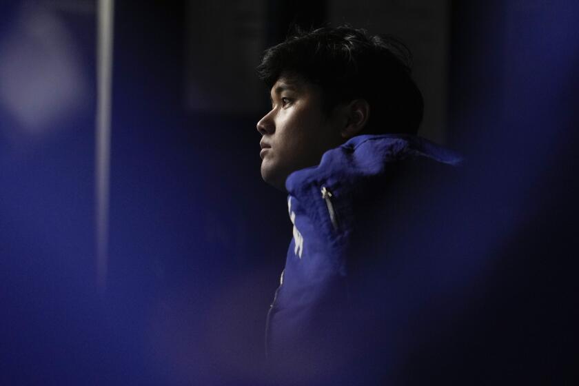 A shadowy shot of Dodgers' Shohei Ohtani watching from in the dugout during Game 5 of the World Series.