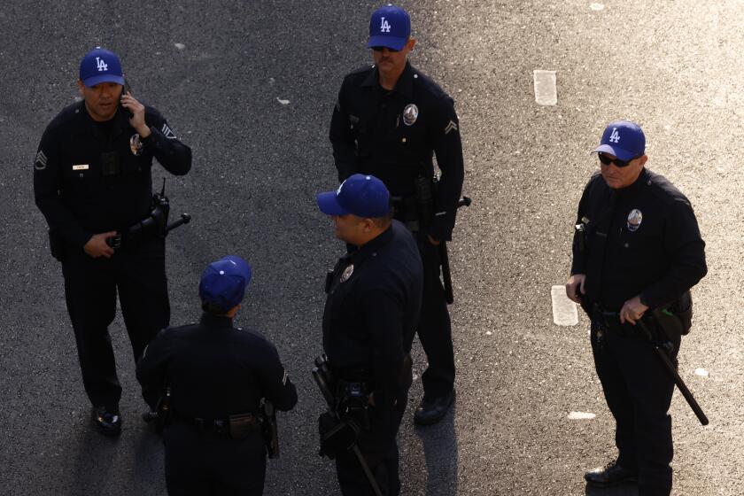 LOS ANGELES, CA - NOVEMBER 1, 2024 - - LAPD officers wear Dodgers cap on the parade route for the Los Angeles Dodgers on 5th Street in downtown Los Angeles on November 1, 2024. (Genaro Molina/Los Angeles Times)