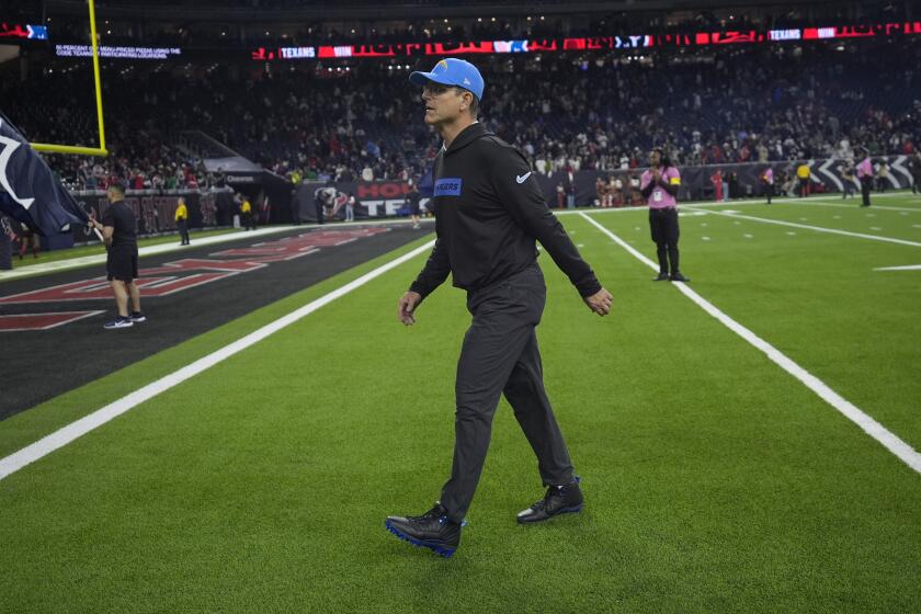 Chargers coach Jim Harbaugh struggles to walk off the field after a playoff loss to the Texans.