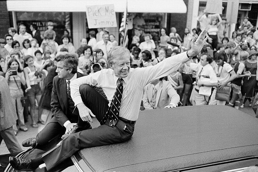 FILE - In this July 31, 1979, file photo, President Jimmy Carter waves from the roof of his car along the parade route through Bardstown, Ky. Carter is sometimes called a better former president than he was president. The backhanded compliment has always rankled Carter allies and, they say, the former president himself. Yet now, 40 years removed from the White House, the most famous resident of Plains, Georgia, is riding a new wave of attention as biographers, filmmakers, climate activists and Carter's fellow Democrats push for a recasting of his presidential legacy. (AP Photo/Bob Daugherty, FIle)