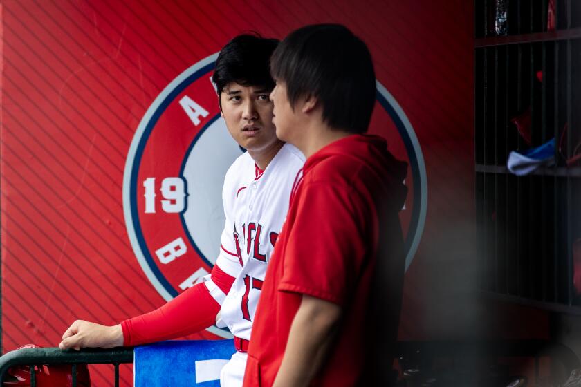 ANAHEIM, CA - JULY 23, 2023: Los Angeles Angels starting pitcher Shohei Ohtani (17) stands in the dugout near his translator during the first inning against the Pittsburgh Pirates on July 23, 2023 in Anaheim, California. (Gina Ferazzi / Los Angeles Times)