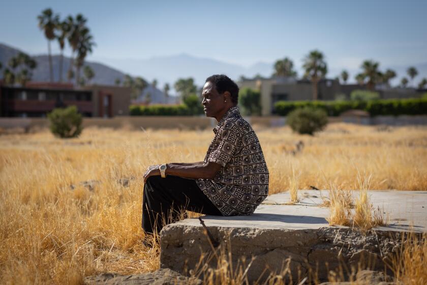 Palm Springs, CA - May 28: Alvin Taylor sits on a remaining foundation of a home in Section 14, as he and his wife Delia Ruiz visit an are in Palm Springs where their family's homes was seized on Tuesday, May 28, 2024 in Palm Springs, CA. (Jason Armond / Los Angeles Times)