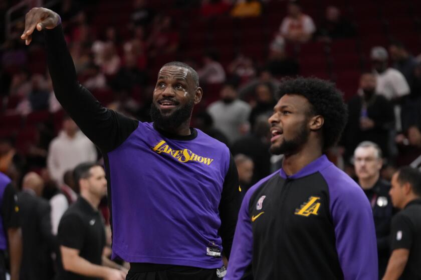 LeBron and Bronny James talk as they warm up before an NBA basketball game.