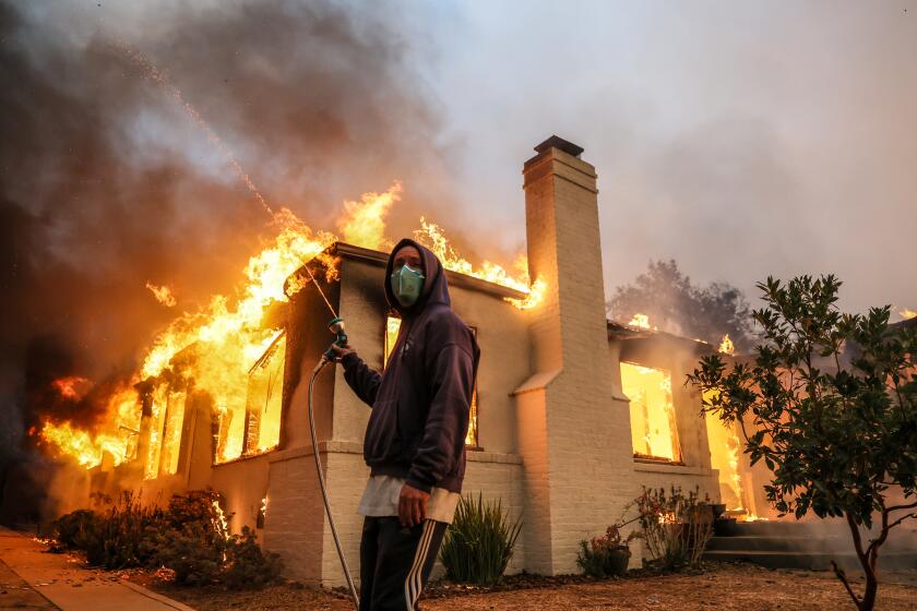 Altadena, CA, Wednesday, Jan 8, 2025 - A resident of La Paz Rd. mans a hose as he tries to prevent the spread of flames from one neighbors house to another. (Robert Gauthier/Los Angeles Times)