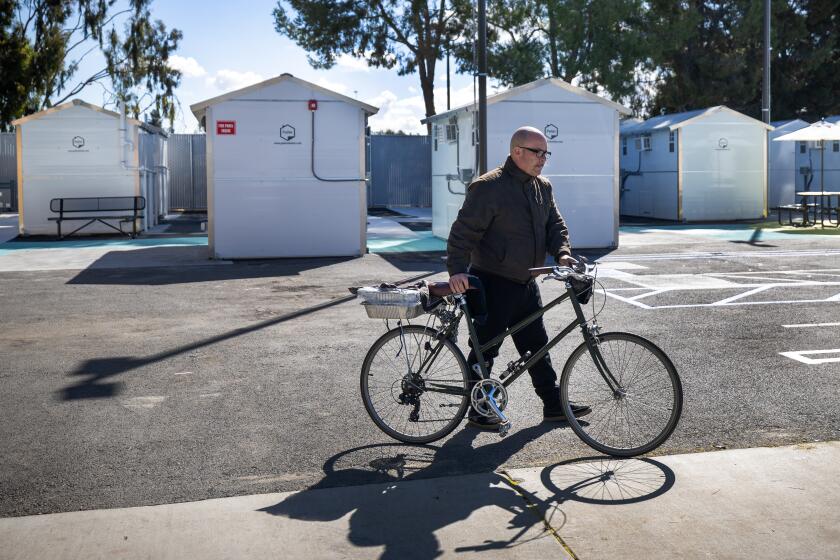 Boyle Heights, CA - February 08: Mariachi musician Ramiro Arana-Beserra, 56, who has been playing his violin at Mariachi Plaza de Los Angeles for 38 years and living in his RV for 3 years on street next to the plaza, heads back to his RV after checking out one of tiny homes he will move into Thursday in the Boyle Heights Tiny Home Village, following a ribbon-cutting ceremony by LA Councilman Kevin de Leon. The project sits on a city-owned lot and marks the third Tiny Home Village in Council District 14. A number of mariachis who became homeless because of the pandemic will be among those living at the village. Photo taken in Boyle Heights Thursday, Feb. 8, 2024. (Allen J. Schaben / Los Angeles Times)