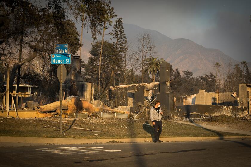 Altadena, CA - January 09: A person walks past burned down homes after the Eaton fire destroyed thousands of homes and businesses in Altadena Thursday, Jan. 9, 2025. (Allen J. Schaben / Los Angeles Times)