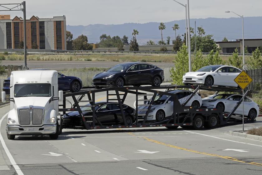 A truck hauling new Tesla vehicles leaves the Tesla factory plant on Monday, May 11, 2020, in Fremont, Calif. The parking lot was nearly full at Tesla's California electric car factory Monday, an indication that the company could be resuming production in defiance of an order from county health authorities. (AP Photo/Ben Margot)