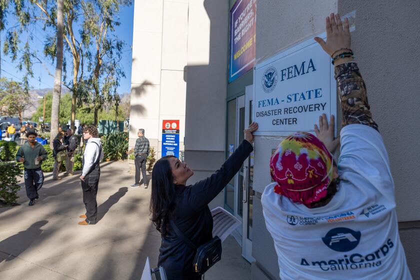 Pasadena, CA - January 14: Workers put up a sign as wildfire victims seek disaster relief services at one of two FEMA Disaster Recovery Centers at the Pasadena City College Community Education Center in Pasadena Tuesday, Jan. 14, 2025. (Allen J. Schaben / Los Angeles Times) FEMA Disaster Recovery Centers opened in Los Angeles County to assist Californians who experienced damage to their primary home, personal property loss or have disaster-caused emergency needs related to the wildfires. At the center, people can get help applying for federal assistance, speak to representatives from state and federal agencies, receive updates on their FEMA application for assistance and learn about the appeals process.