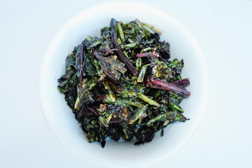 A white bowl of charcoal-grilled beet greens on a white table at East Hollywood restaurant Fountain Grains & Greens.