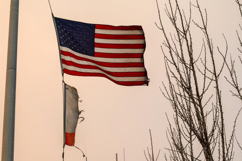 Altadena, CA, Wednesday, Jan 8, 2025 - A burned California flag waves under a U.S. flag outside an LA County Sheriff substation. (Robert Gauthier/Los Angeles Times)