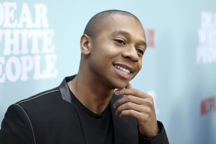 DeRon Horton smiles while touching his chin during a red-carpet premiere