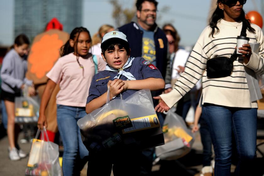 LOS ANGELES, CA - NOVEMBER 23: Beckett Wienckowski (cq), 8, of Northridge, with Cub Scout Pack 911, volunteers at Big Sunday's 11th Annual Thanksgiving Stuffing Event at Baldwin Hills Elementary School on Wednesday, Nov. 23, 2022 in Los Angeles, CA. The Big Sunday organization will host its 11th annual ``Big Thanksgiving Stuffing Event -- a Festival of Gratitude.'' More than 1,500 volunteers will sort food and hand out bags of food to families in need. (Gary Coronado / Los Angeles Times)