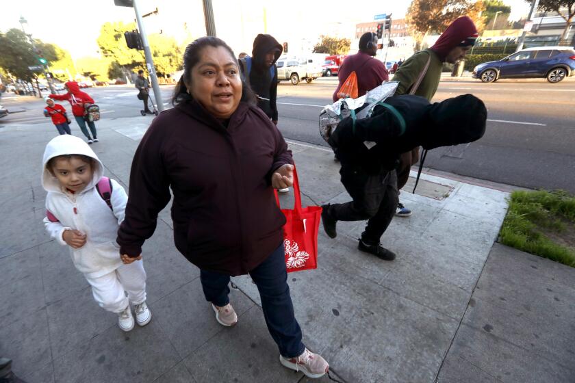 LOS ANGELES, CA - DECEMBER 12, 2024 - - Maria De Los Angeles Cruz walks her daughter, Alexandra Nicole, 6, to school down the gritty sidewalks of Wilshire Blvd. in the Westlake District on December 5, 2024. Cruz and her daughter have seen homeless sleeping on the sidewalk, people doing drugs, and some, defecating in planters near their apartments on their daily walks to and from school. (Genaro Molina/Los Angeles Times)