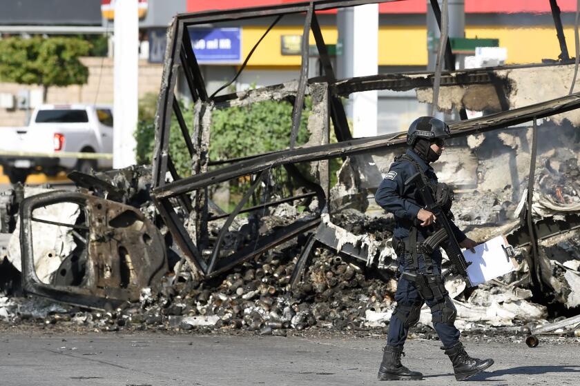 A policeman walks past a burnt vehicle after heavily armed gunmen waged an all-out battle against Mexican security forces in Culiacan, Sinaloa state, Mexico, on October 18, 2019. - Mexico's president faced a firestorm of criticism Friday as his security forces confirmed they arrested kingpin Joaquin "El Chapo" Guzman's son, then released him when his cartel responded with an all-out gun battle. (Photo by ALFREDO ESTRELLA / AFP) (Photo by ALFREDO ESTRELLA/AFP via Getty Images)