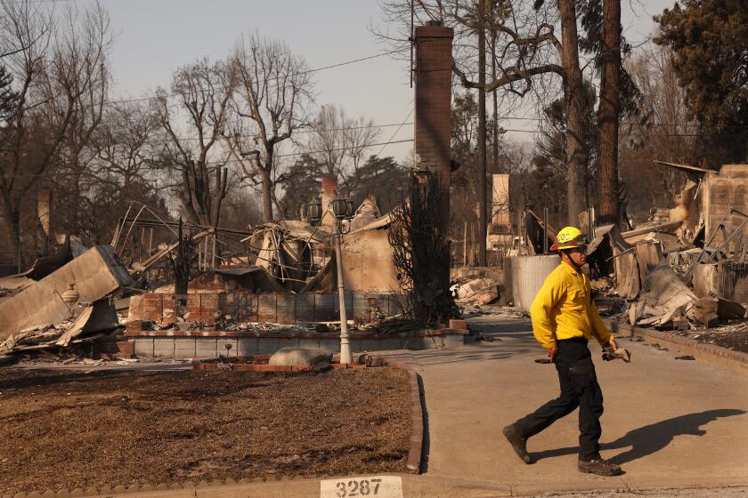 ALTADENA, CA, JANUARY 10, 2025: The charred remains of 83-year-old Erliene Kelley's home on Tonia Avenue in Altadena, at left, burned by the Eaton Fire, on Friday, January 10, 2025. It has been 48 hours since her granddaughter Briana Navarro has heard from her. (Christina House / Los Angeles Times)