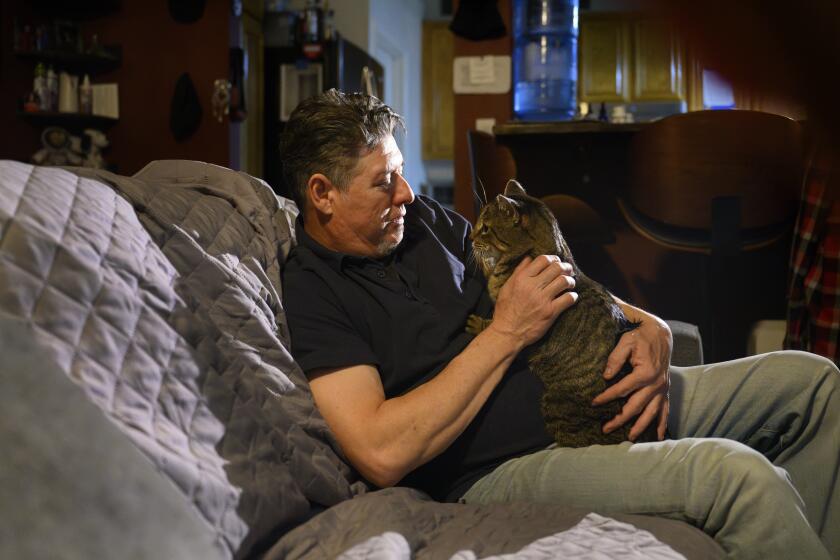 SAN BERNARDINO, CA - JANUARY 2, 2025: Joseph Journell of San Bernardino cuddles with his cat Big Boy who is recuperating from the H5N1 bird flu on January 2, 2025 in San Bernardino, California. Journell regularly fed his cats raw milk from Raw Farm, LLC and in late November his oldest cat Alexander died and then three days later his cat Tuxie died. Big Boy spent 8 days in a veterinarian hospital.(Gina Ferazzi / Los Angeles Times)