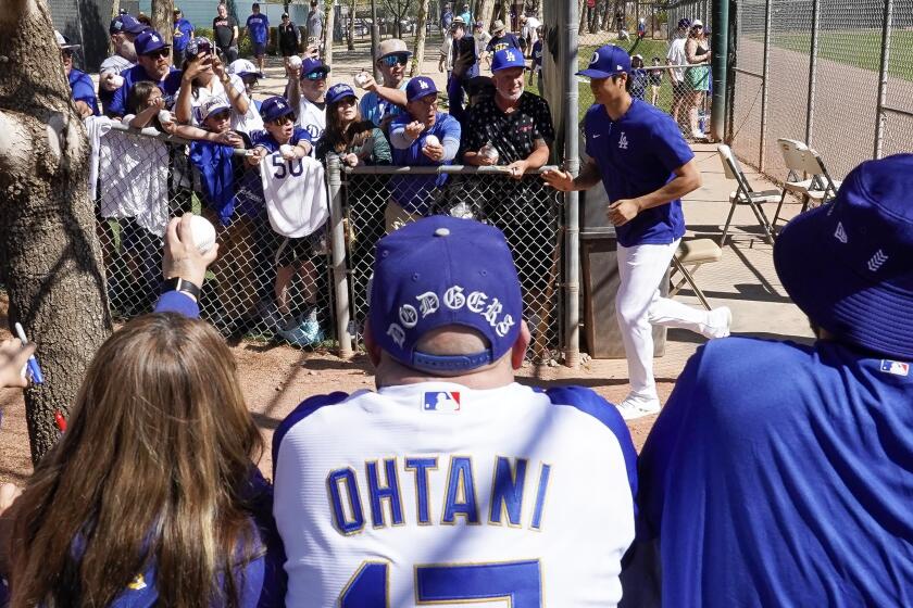 Los Angeles Dodgers designated hitter Shohei Ohtani runs past fans as he participates in spring training baseball workouts at Camelback Ranch in Phoenix, Tuesday, March 12, 2024. (AP Photo/Darryl Webb)