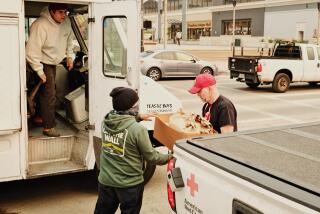 Two Yeastie Boys employeed hand bags of bagels and schmear to a Red Cross representative at the Pasadena Convention Center