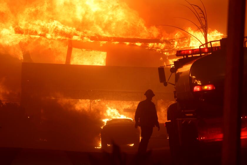 Malibu, California January 8, 2025-A Torrance firefighter watches as a house burns from the Palisades Fire on Shoreheights Drive in Pacific Palisades Tuesday. (Wally Skalij/Los Angeles Times)