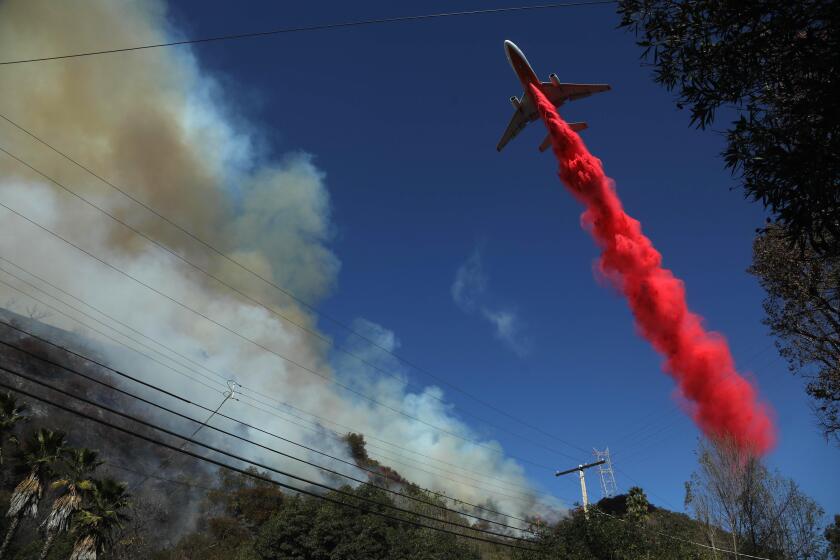 BRENTWOOD, CA - JANUARY 11, 2025 - - An aircraft drops fosscheck on the the Palisades Fire as it tears through Mandeville Canyon in Brentwood on Saturday. (Genaro Molina / Los Angeles Times)