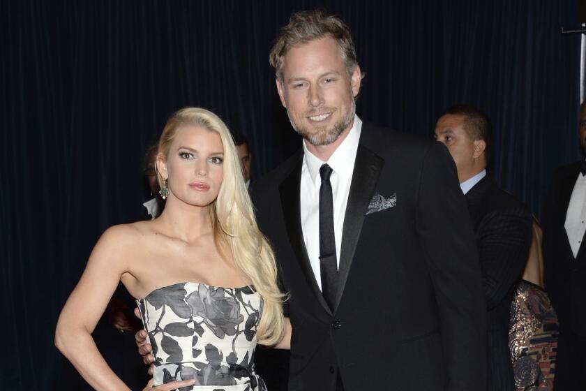 Jessica Simpson wears a black and white strapless gown poses with husband Eric Johnson  in a black suit