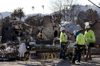 ALTADENA, CA - JANUARY 15, 2025 - - Workers with Southern California Edison attach lines to a telephone pole among the ruins of a structure destroyed by the Eaton fire in Altadena on January 15, 2025. (Genaro Molina/Los Angeles Times)