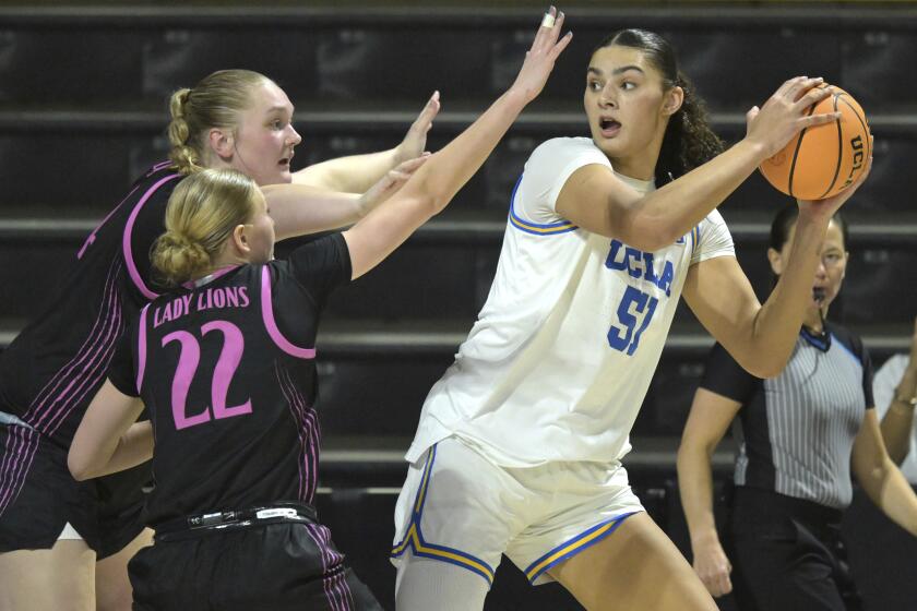 UCLA center Lauren Betts looks to pass around pressure from Penn State center Gracie Merkle and guard Alli Campbell.