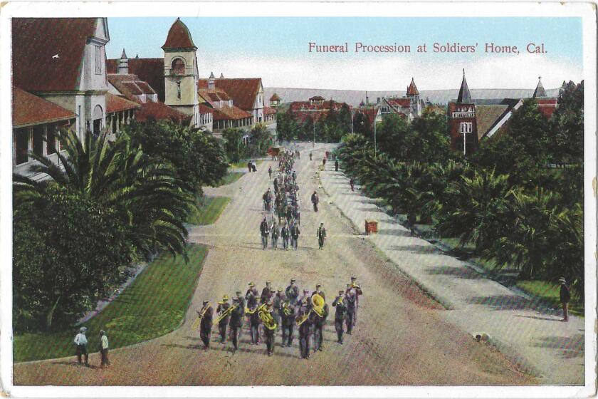 Uniformed men march along a wide path. At the front of the column, the marchers have horns and other instruments.