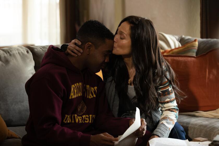 A mother kisses her teenage son on the forehead.